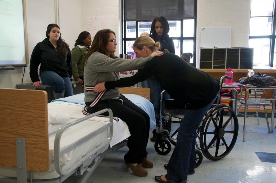 Pictured: Students learn how to assist patients into a wheelchair.